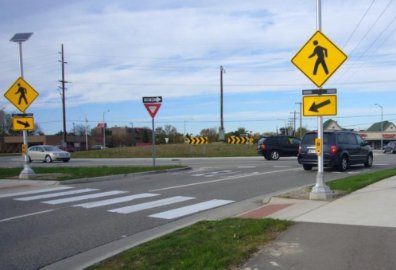 Crosswalk at a roundabout entry with pedestrian warning signs and a yield sign