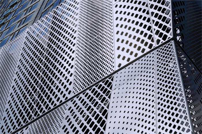 Silver metal panels perforated with rows of holes, set at angles to each other.