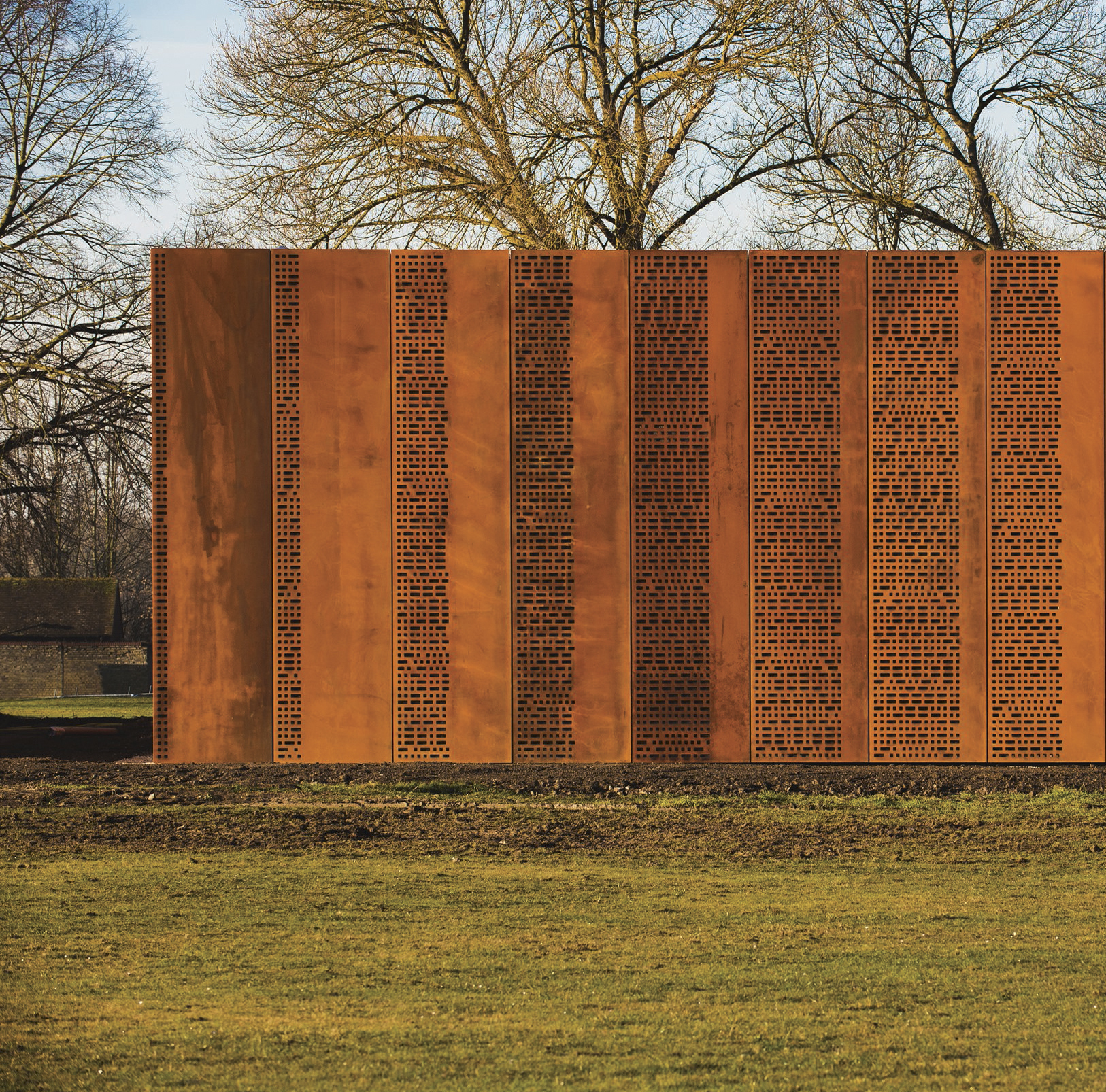 Rust-colored weathered steel panel with rows of small cutouts.