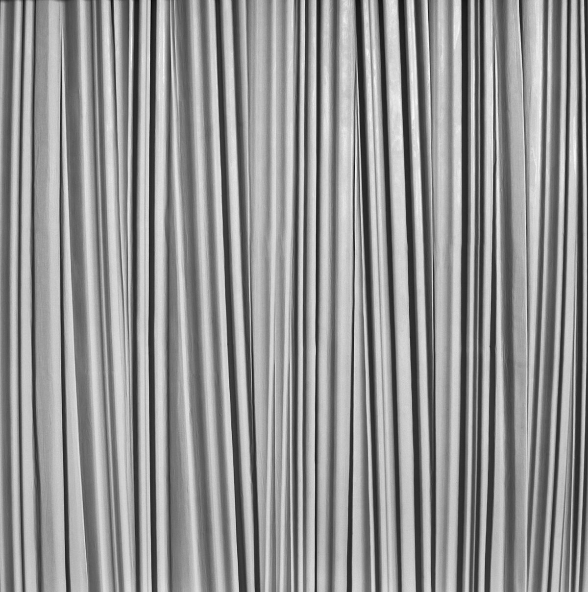 Concrete wall texture with thin, irregular vertical ridges of varying widths, giving a rough, organic look. 